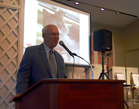 MSPCA President Carter Luke addresses the guests as images of animals up for adoption rotate on the screen behind him.